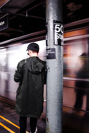 Man waiting at 50th Street subway station with passing train