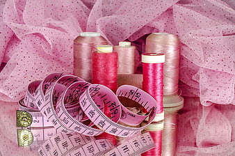 Pink sewing supplies with thread spools and measuring tape