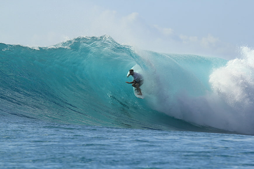 Surfer riding inside a large turquoise barrel wave