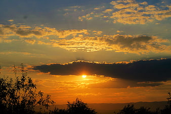 Golden sunset with dramatic clouds and silhouetted trees