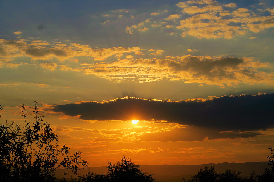 Golden sunset with dramatic clouds and silhouetted trees