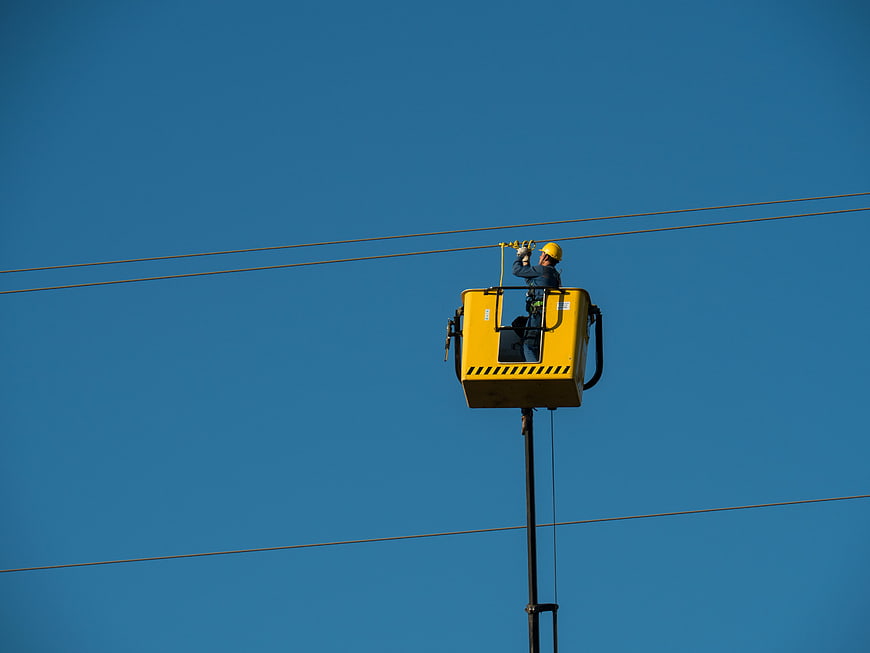 Electrician Working On High Voltage Power Lines In Aerial Lift