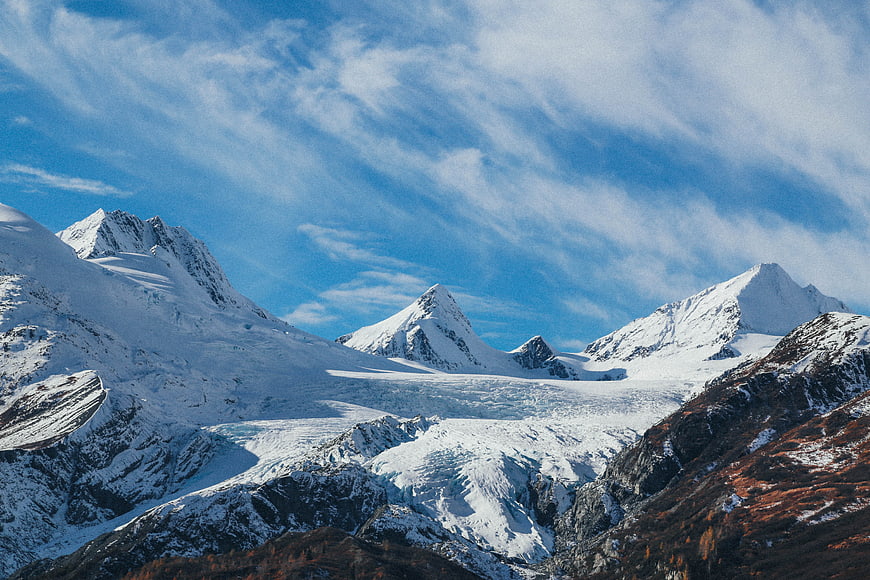 Snow-Capped Mountain Peaks and Glacier Under Blue Sky