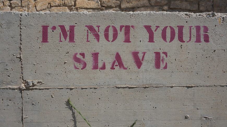Pink stencil graffiti reading I'm not your slave on concrete wall