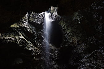Mystical waterfall cascading into a dark cave interior
