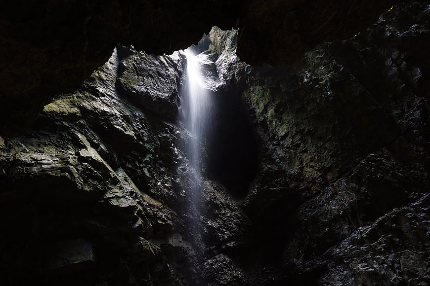 Mystical waterfall cascading into a dark cave interior