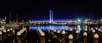 Night view of illuminated bridge and marina with dock pilings