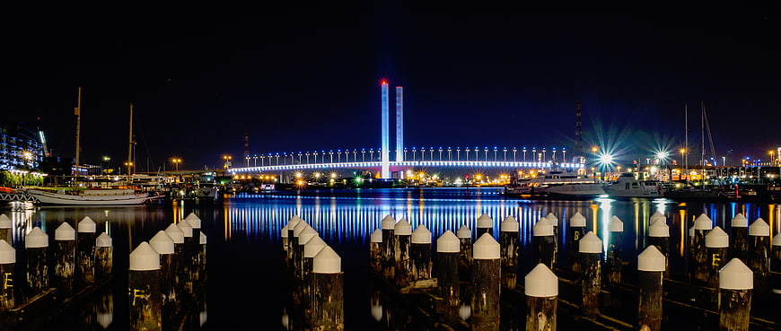 Night view of illuminated bridge and marina with dock pilings