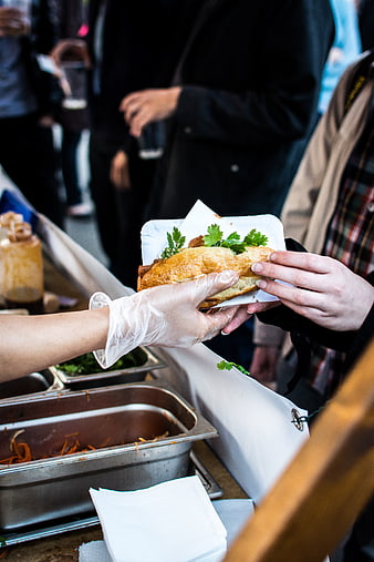 Hands serving fresh Vietnamese Banh Mi sandwich at food festival