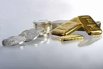 Gold bars and silver coins on reflective surface