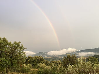 Vibrant Rainbow Arching Over Misty Mountain Valley