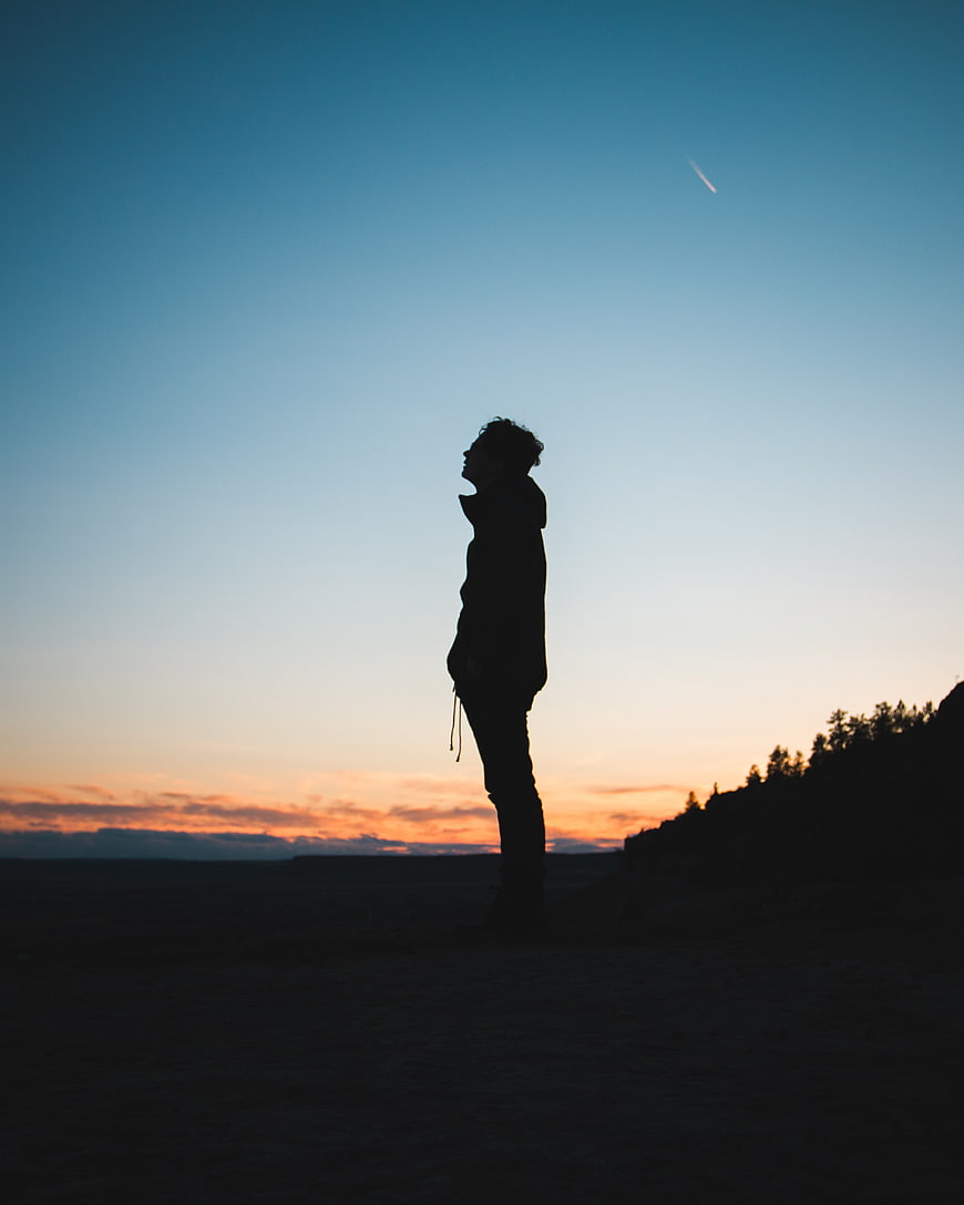 Silhouette of Man Looking Up at Sunset Sky