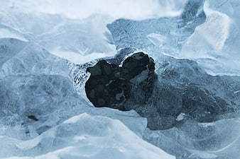 Close-up of dark water hole in frozen blue ice