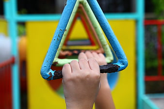 Child's hands gripping colorful playground equipment