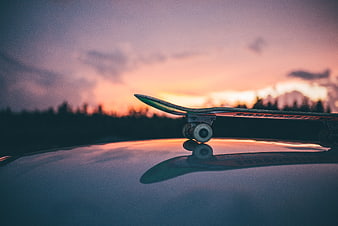 Skateboard on Car Hood at Sunset with Reflection