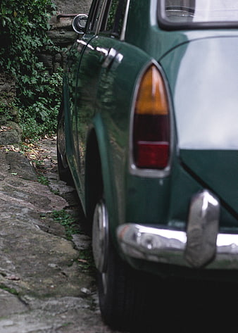 Vintage Green Car Parked on Cobblestone Street