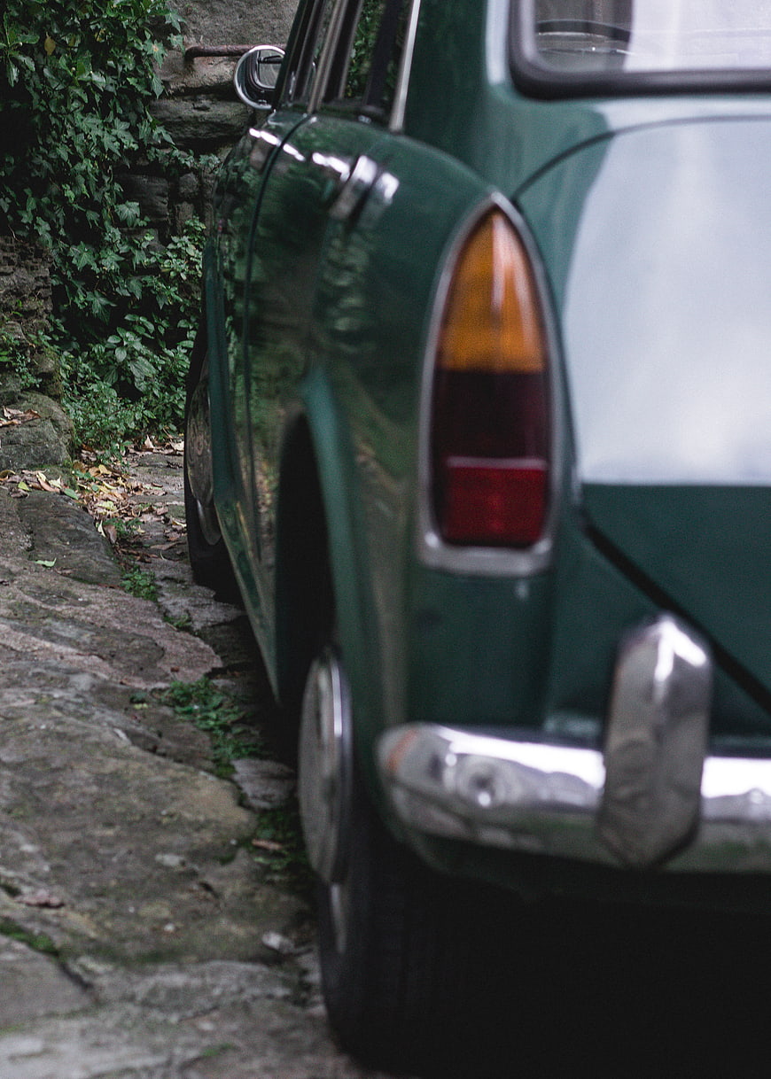 Vintage Green Car Parked on Cobblestone Street