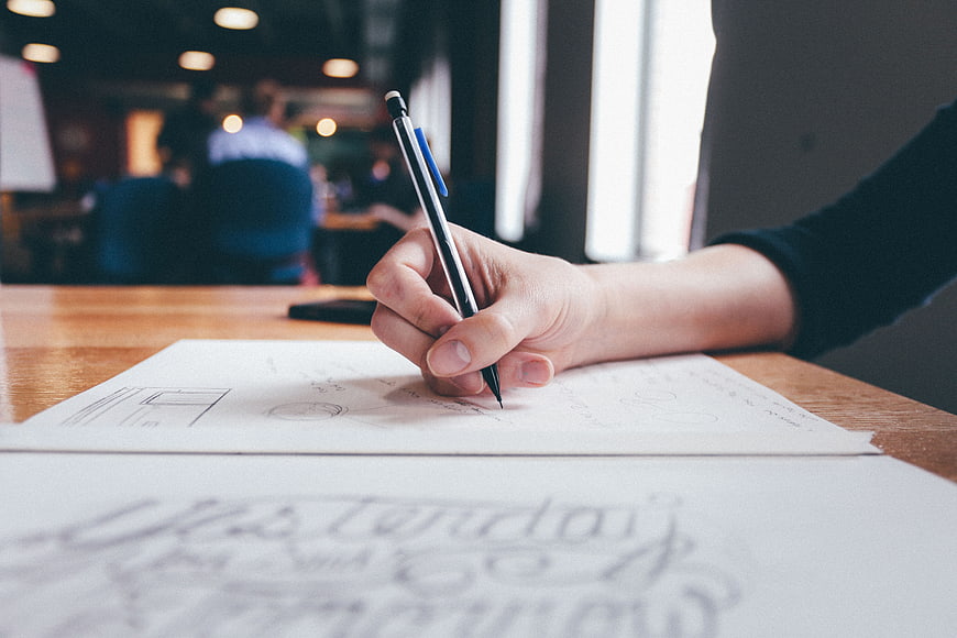 Hand sketching business diagrams on paper at office desk