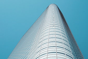 Low angle view of modern glass skyscraper against blue sky