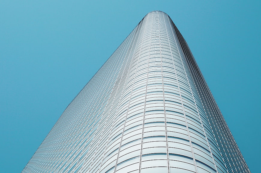 Low angle view of modern glass skyscraper against blue sky