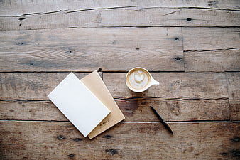 Flat lay of coffee, notebook, and pen on rustic wood