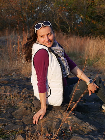 Smiling Woman Sitting on Rocks in Autumn Landscape