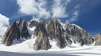 Majestic jagged mountain peaks covered in snow under blue sky