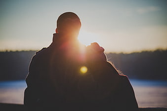 Silhouette of couple embracing at sunset by the water