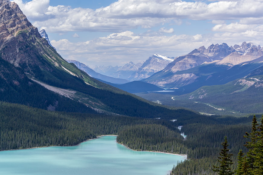 Turquoise glacial lake surrounded by pine forests and rugged mountains