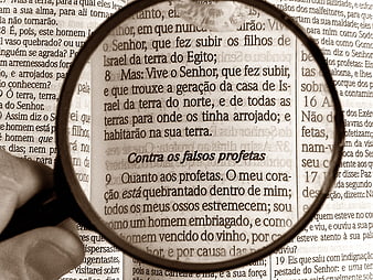 Magnifying glass focusing on Portuguese Bible text about false prophets