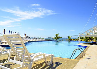 White lounge chair by resort pool with ocean view