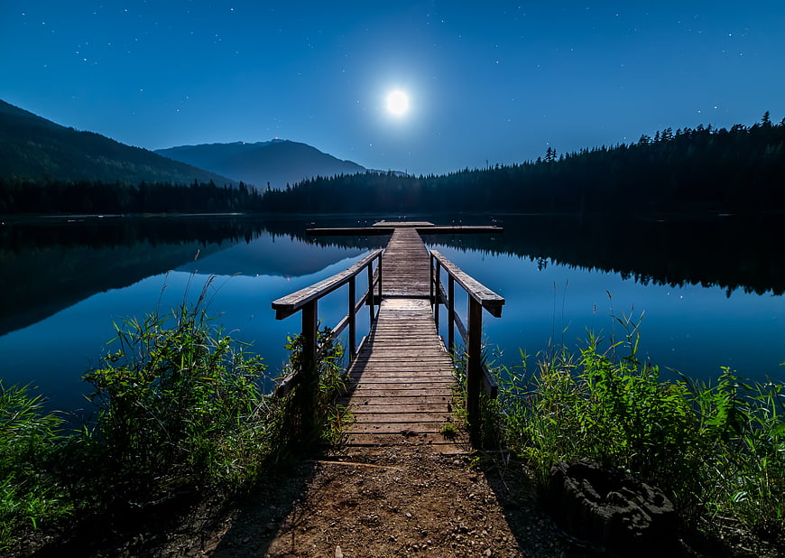 Wooden Dock on Lake Under Full Moon and Starry Night Sky
