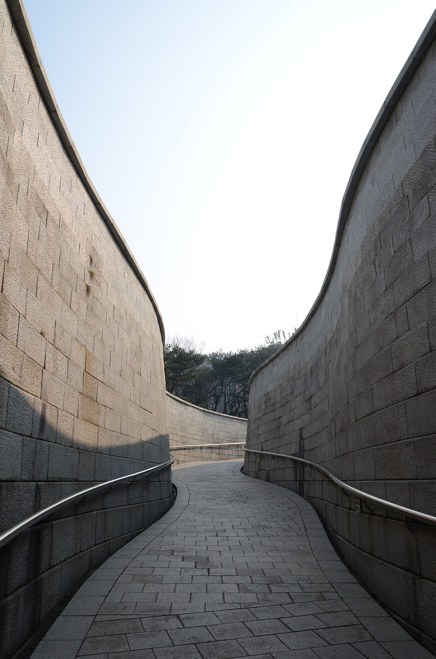 Curved stone pathway with high walls and sky