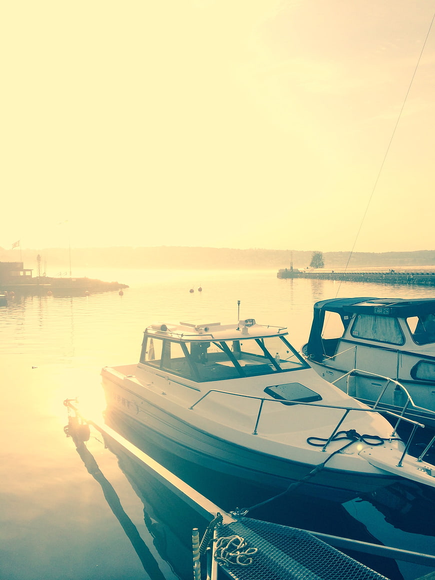 White motorboat docked in calm harbor at golden hour