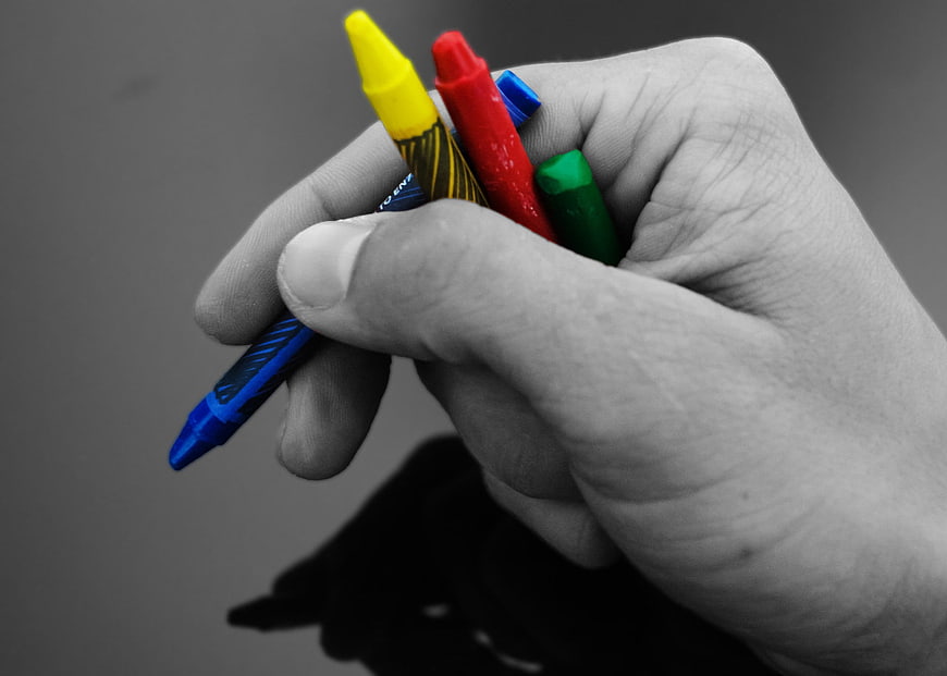 Hand Holding Colorful Crayons Against Black And White Background