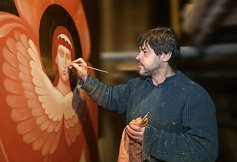 Artist painting a religious icon of an angel in a workshop