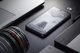 Smartphone and Camera Lens on Dark Wooden Desk