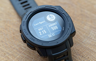 Close-up of black GPS smartwatch showing hiking statistics on wooden surface