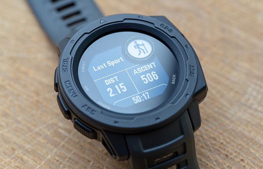 Close-up of black GPS smartwatch showing hiking statistics on wooden surface