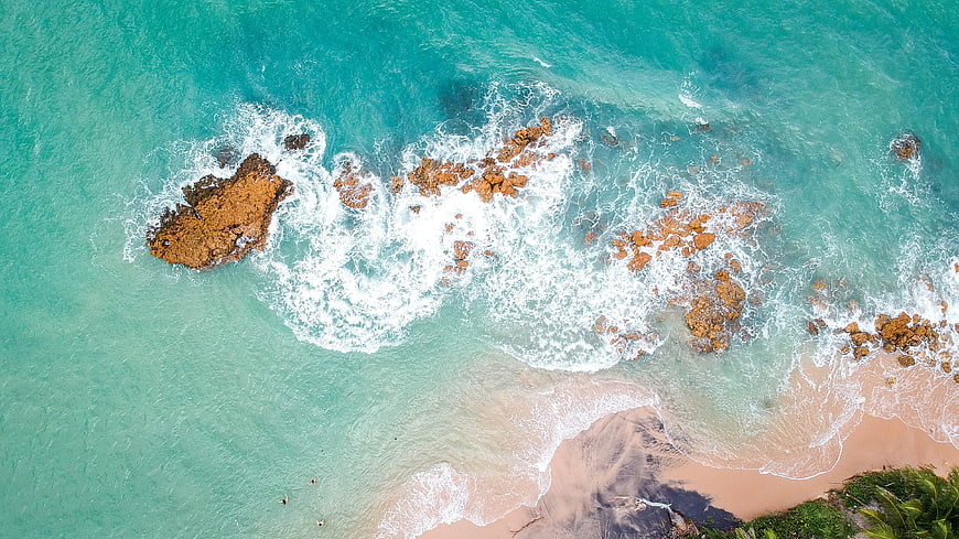 Aerial View of Turquoise Ocean Waves Crashing on Rocky Coastline