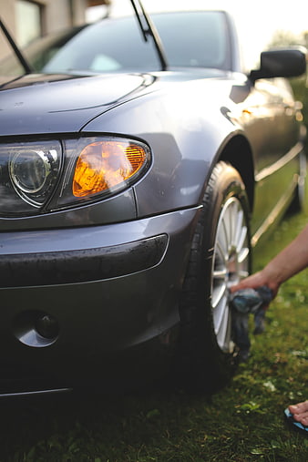 Close-up of person cleaning car wheel with cloth