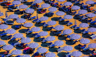Aerial view of blue and white striped beach umbrellas on sand