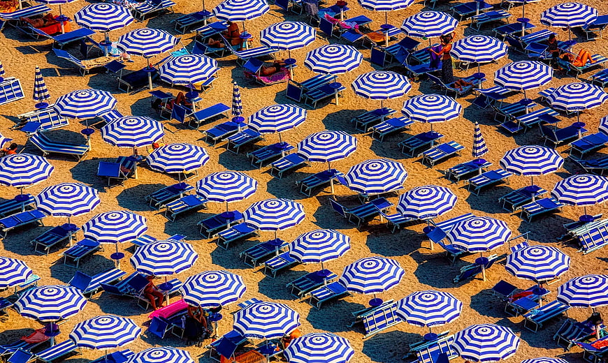 Aerial view of blue and white striped beach umbrellas on sand