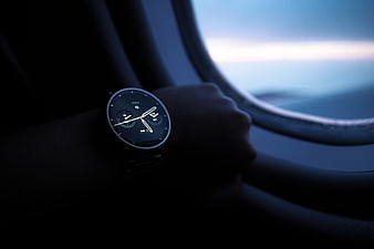 Smartwatch on wrist inside airplane window at dusk