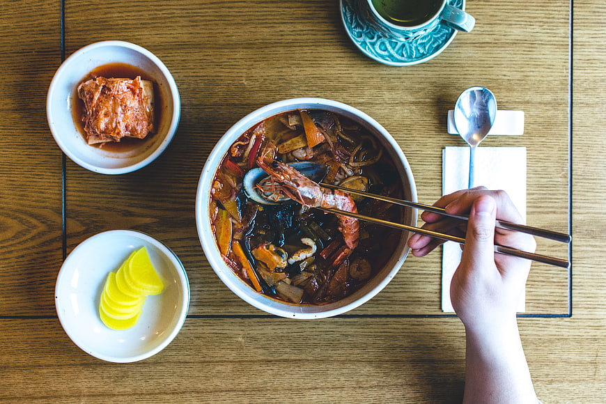 Top View of Korean Seafood Stew with Kimchi and Pickles