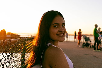 Smiling Brunette Woman at Sunset by Waterfront