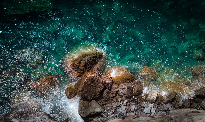 Aerial View of Turquoise Waves Crashing on Rocky Coast