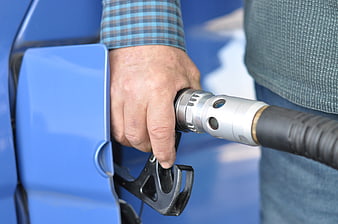 Close-up of hand holding gas pump nozzle refueling blue car
