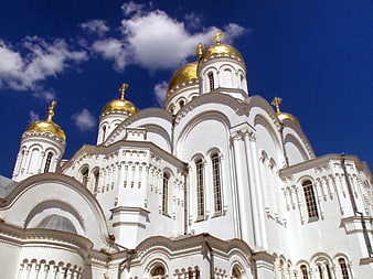 White Orthodox Church with Golden Domes Against Blue Sky