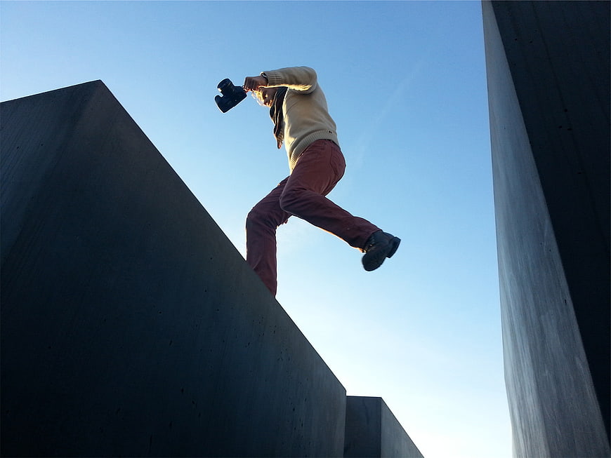 Man Jumping with Camera Between Concrete Slabs